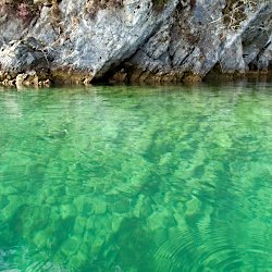 Klarer türkisfarbener See vor Felswand